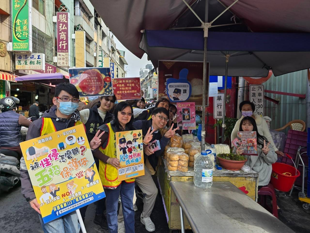 中市婦幼警與志工在豐原市場踩街宣導與店家合影。