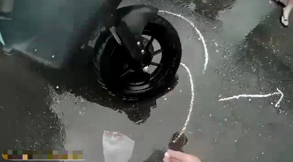 照片2 因大雨狂下且車流湧現，保大員警見狀立刻在車禍現場路面，用白色粉筆劃註車輛交通事故記號及拍攝現場照片。