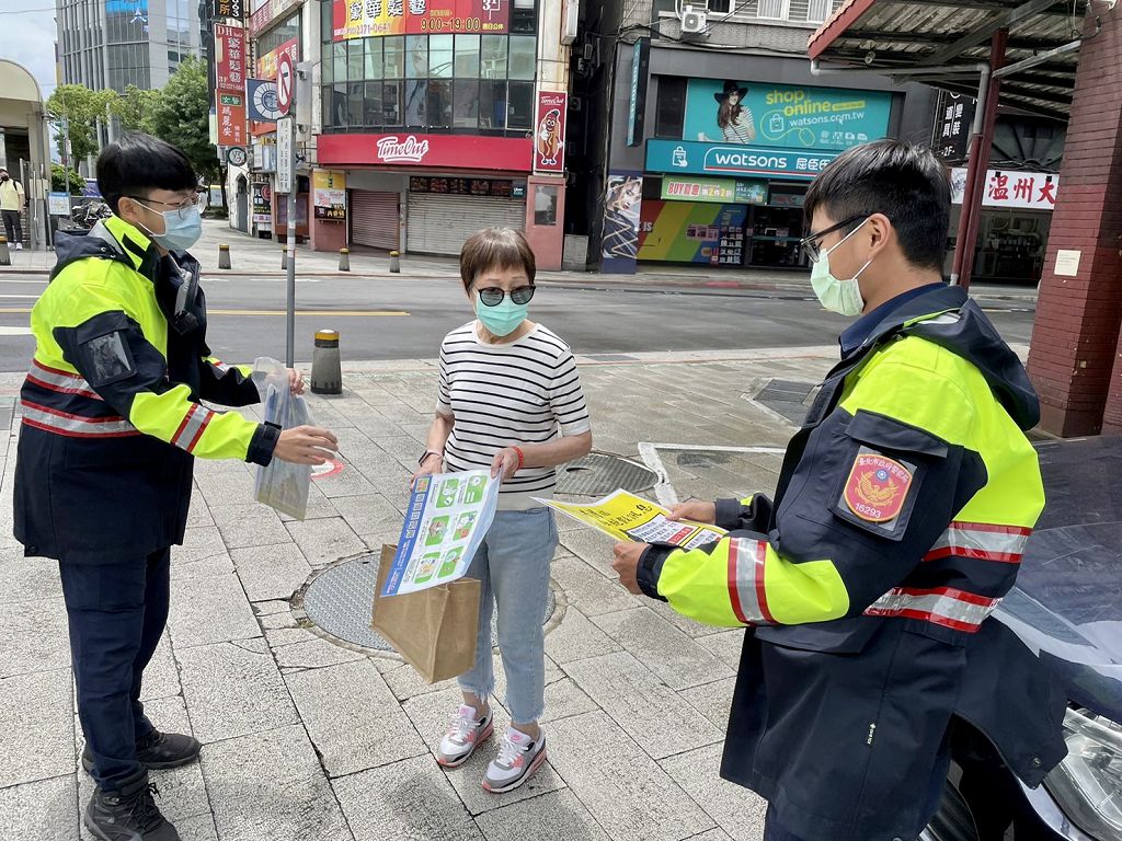 照片2 臺北市保安警察大隊員警手持宣導海報，以標語提醒民眾，小心防疫期間常見的簡訊詐騙。